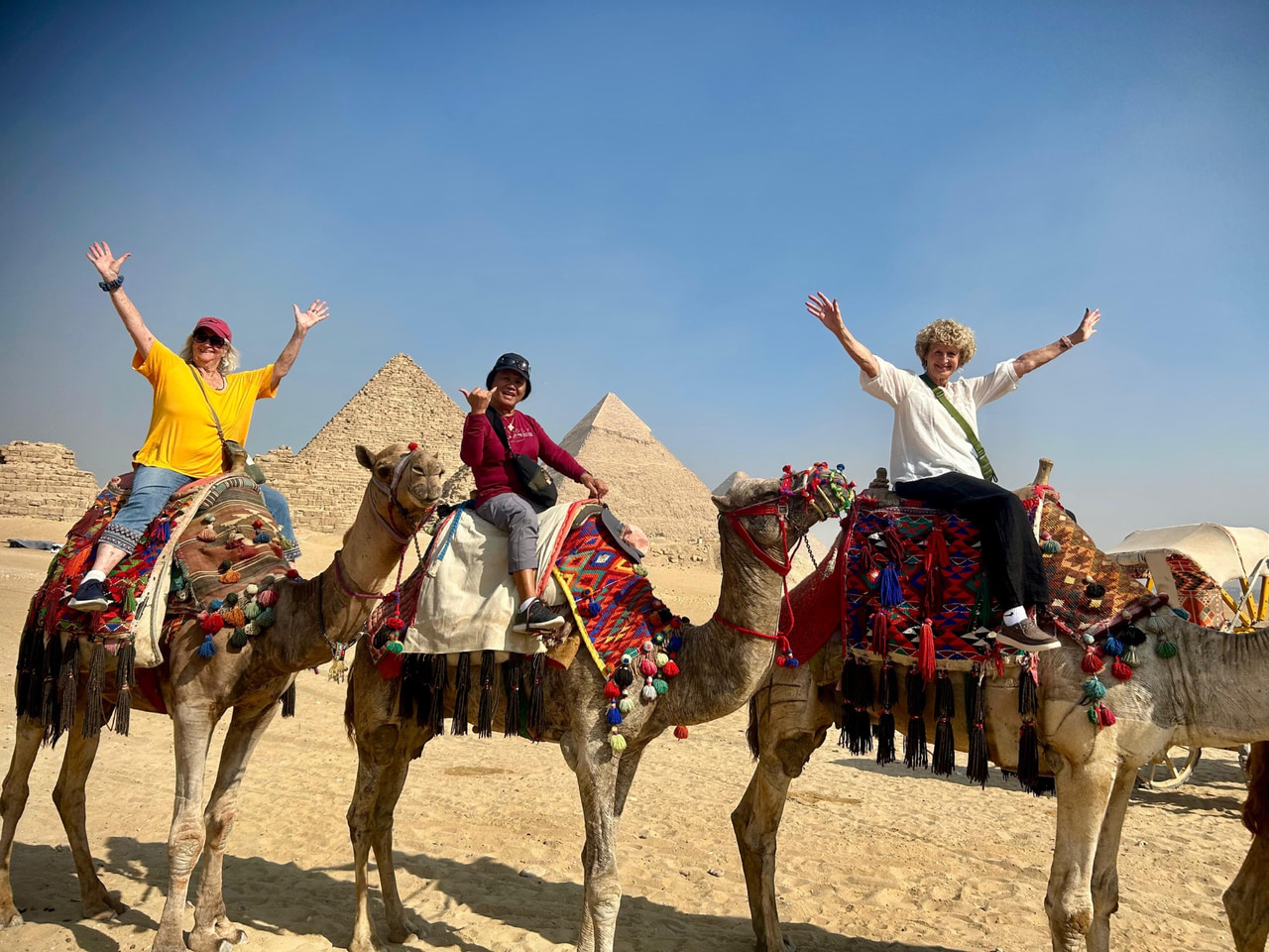 Travelers riding camels in front of the Pyramids of Giza