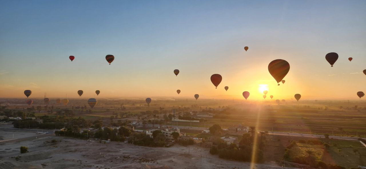 Hot air balloons drifting over the fields at sunrise near Luxor